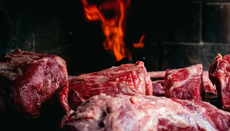 Cortes crudos sobre la parrilla con la llama del fuego atrás